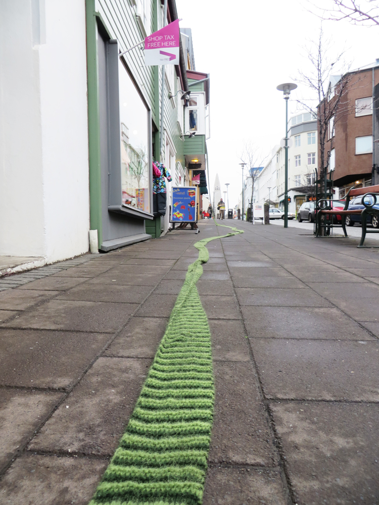 a striped green scarf unrolled on the sidewalk of brautarholt in reykjavik