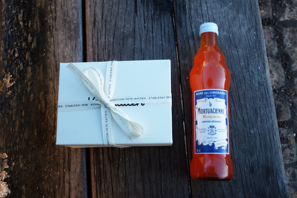 A Vete-Katten box and a fancy soda on a bench on Stockholm Harbor