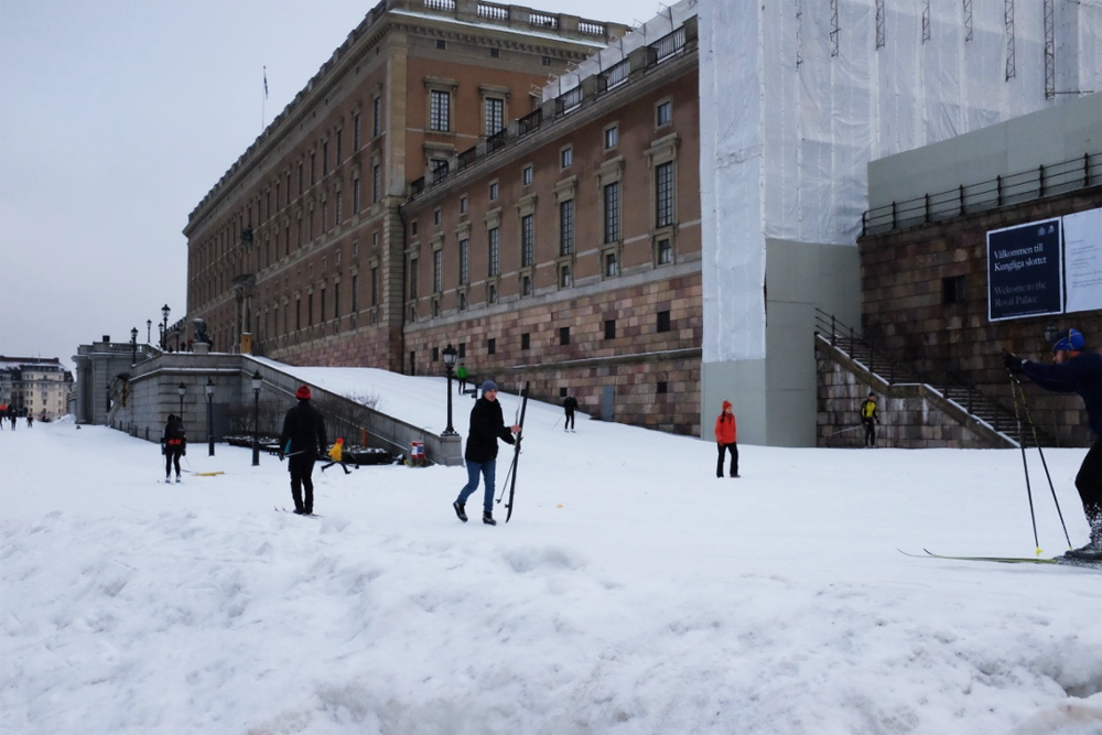 A snowy slope and skiers behind Stockholm's Royal Palace