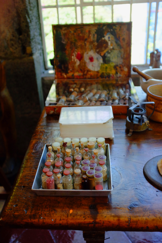 Frida Kahlo's glitter collection, on a wood counter in her house, in front of a paint set