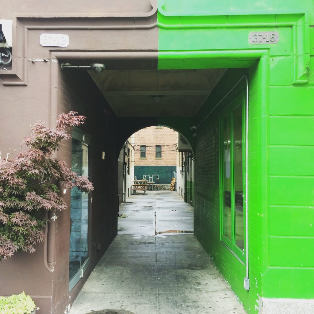 A rectangular doorway leading to a courtyard, green on one side and tan on the other