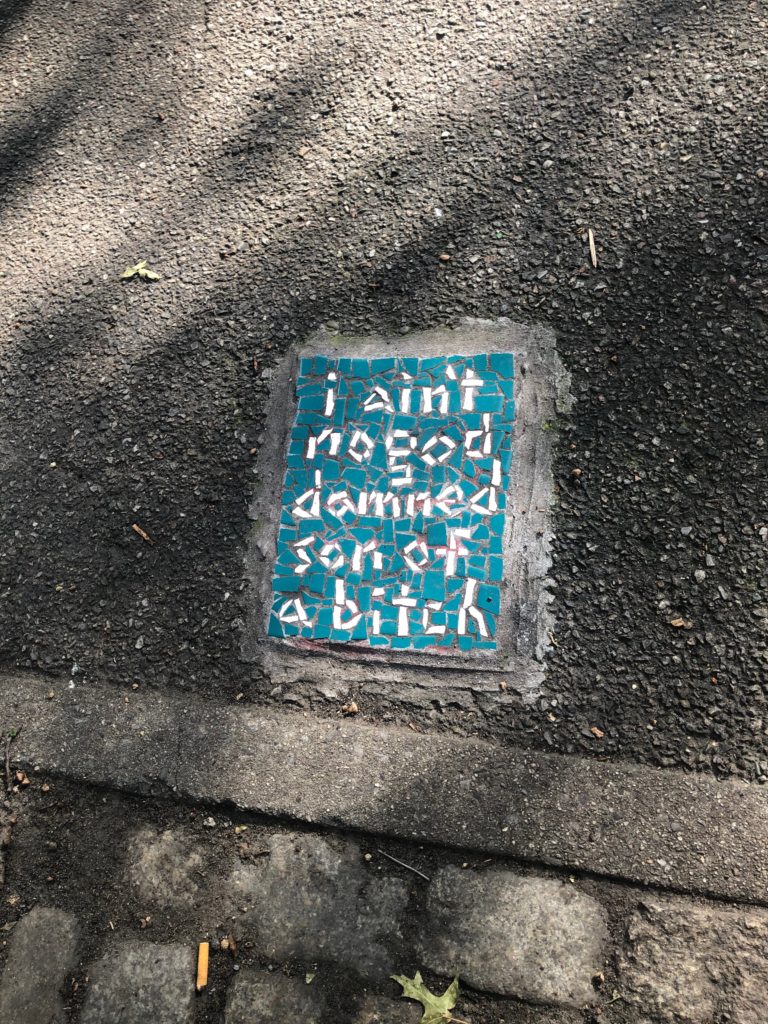 a mosaic on a sidewalk reads "I ain't no goddamned son of a bitch"