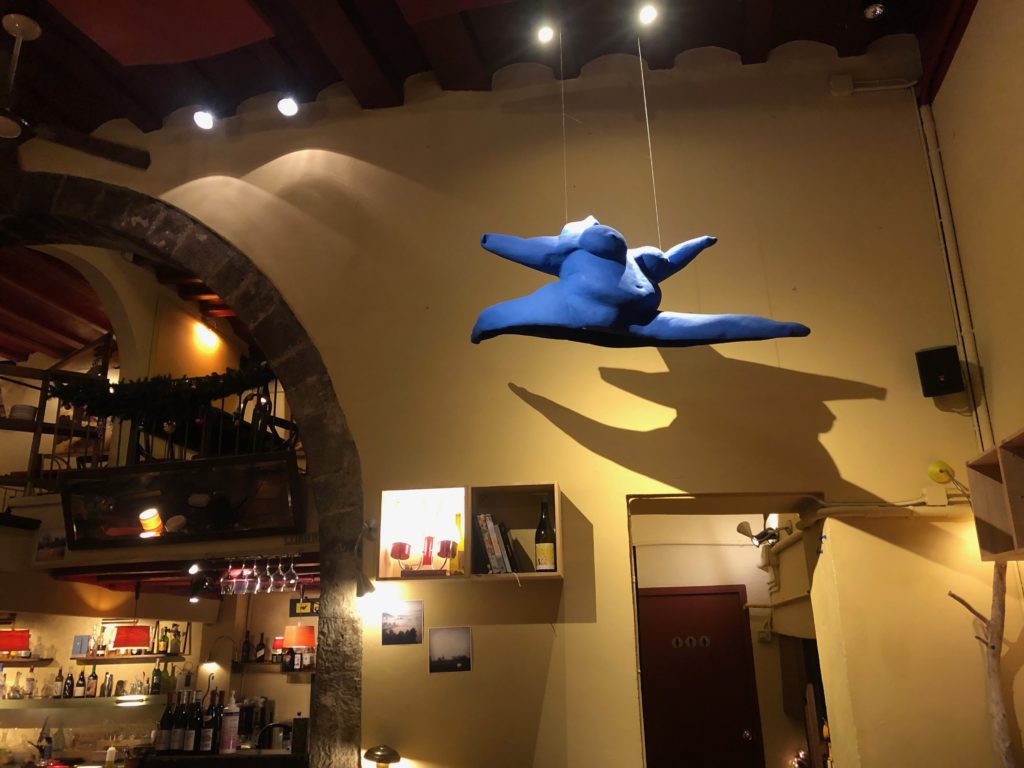 The interior of a Barcelona restaurant, with a hanging sculpture of a voluptuous woman dancing through the air