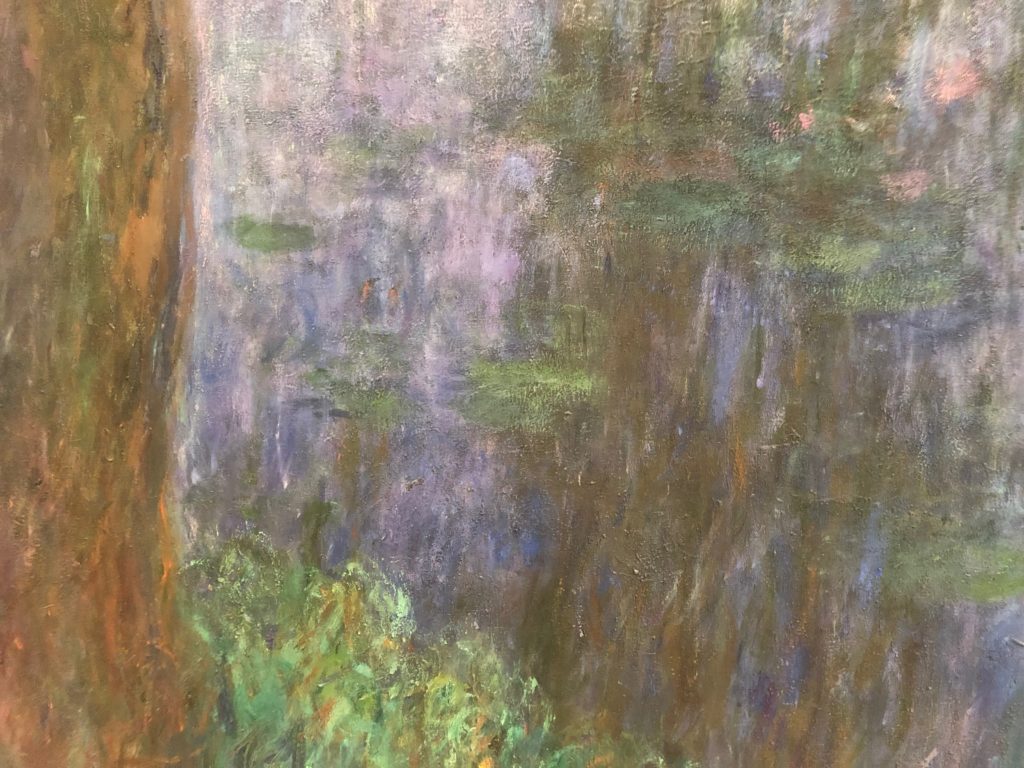 A closeup of a small part of a Monet waterlilies painting with streaks of purple, brown, and green