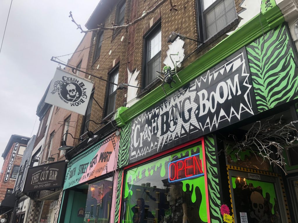 Storefronts, including a black-and-green one called Crash Bang Boom and another reading South Street Art Mart