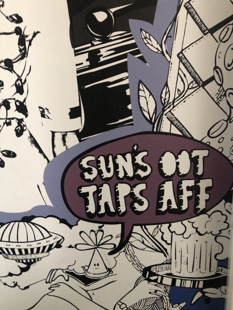 Detail of a hotel room mural with a speech bubble containing the words "SUNS OOT TAPS AFF"